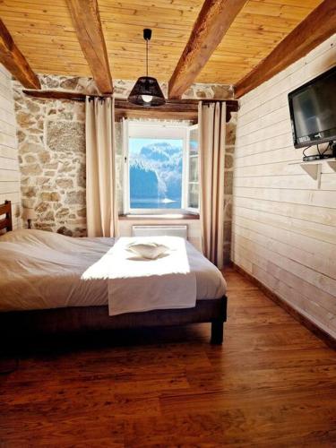 - une chambre avec un lit, une fenêtre et une télévision dans l'établissement Gîte d'Oustrac, vue imprenable sur Lac de Maury, à Saint-Amans-des-Cots