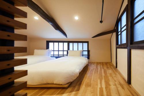 two beds in a room with two windows at Mibu Hanabusa House in Kyoto