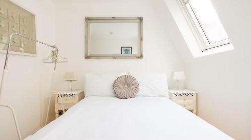 a white bedroom with a bed and two windows at Notting Hill Luxury Duplex in London