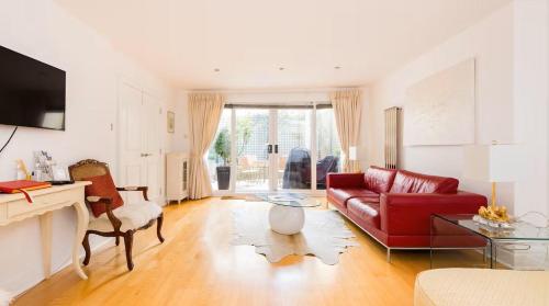 a living room with a red couch and a table at Notting Hill Luxury 3BR Duplex Modern Spacious Gem in London