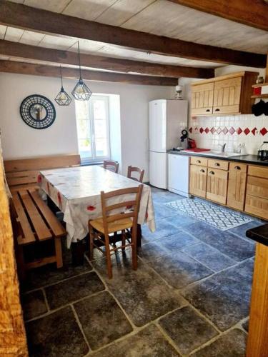 une cuisine avec une table, des chaises et un réfrigérateur dans l'établissement Gîte d'Oustrac, vue imprenable sur Lac de Maury, à Saint-Amans-des-Cots