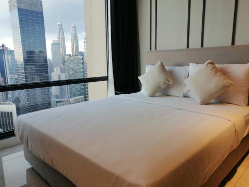 een bed met witte kussens in een kamer met een raam bij Axon Apartment Bukit Bintang At KL in Kuala Lumpur