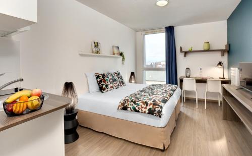 a bedroom with a bed and a desk and a kitchen at Ténéo Apparthôtel Bordeaux Maritime - Cité du vin in Bordeaux
