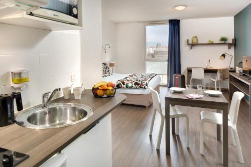 a kitchen and living room with a sink and a table at Ténéo Apparthôtel Bordeaux Maritime - Cité du vin in Bordeaux