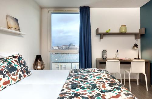 a bedroom with a bed and a desk and a window at Ténéo Apparthôtel Bordeaux Maritime - Cité du vin in Bordeaux