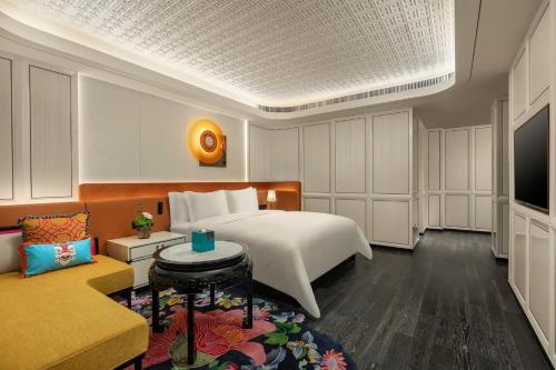 a bedroom with a bed and a tv and a couch at Hotel Indigo Guangzhou Haixinsha by IHG - Free Shuttle Bus to Canton Fair Complex during Canton Fair period in Guangzhou