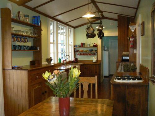 una cocina con un jarrón de flores sobre una mesa en Endless Summer Lodge en Ahipara