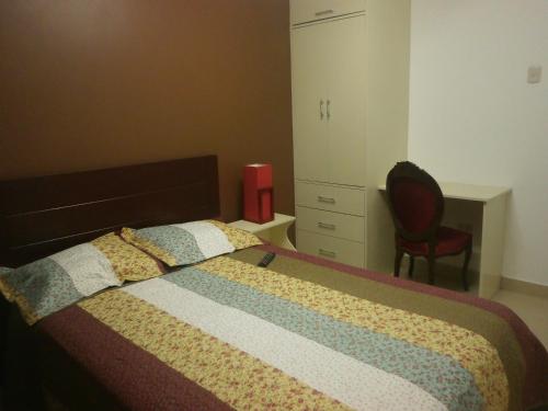 a bedroom with a bed with a dresser and a chair at Strenua - Las Quintanas in Trujillo