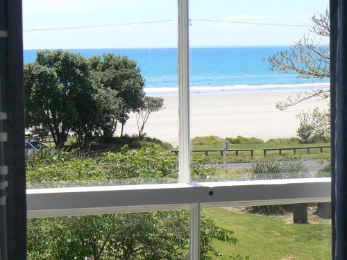 a view of the beach from a window at Endless Summer Lodge - Guesthouse in Ahipara