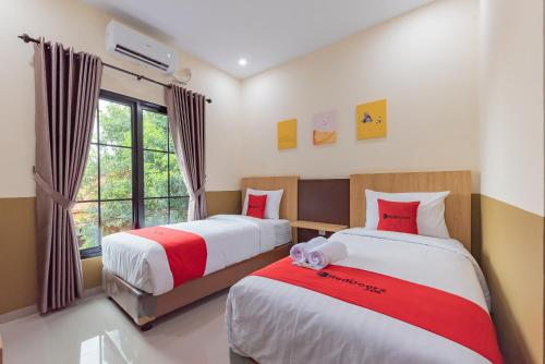 a bedroom with two beds and a window at RedDoorz Plus @ La Asiana Guest House in Kanggraksan