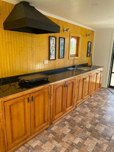 cocina con armarios de madera y encimera negra en HOTEL BOUTIQUE CASA BLANCA, en Chillán