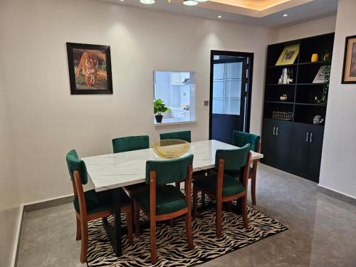 a dining room with a white table and green chairs at Voyager 002 in Nairobi