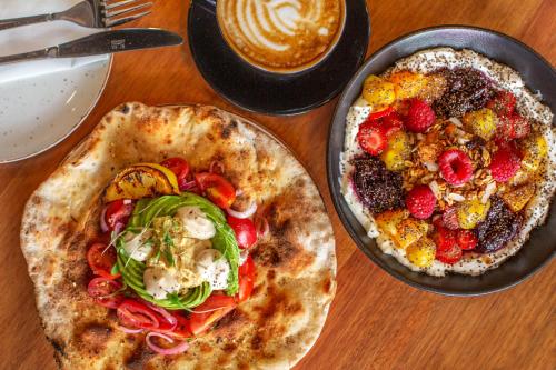 a table with two pizzas and a bowl of fruit at The Tokyo Aparthotel by Totalstay in Cape Town
