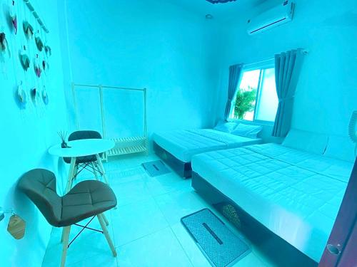 ein blaues Zimmer mit 2 Betten, einem Tisch und einem Stuhl in der Unterkunft Nguyên Căn Homestay OHANA - Đảo Phú Quý in Cu Lao Thu