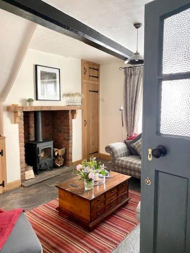 a living room with a table and a fireplace at Aragon Cottage in Ludlow