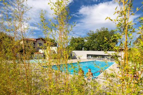 un homme debout en face d'une piscine dans l'établissement Chez Benjamin - Appt terrasse avec piscine commune, à La Teste-de-Buch