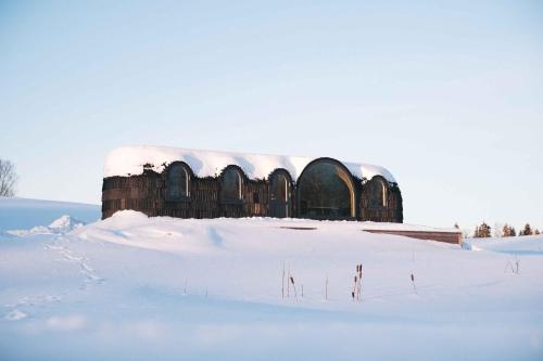 a building with snow on top of a snow covered field at KODAS Hubane iglumajutus järve kaldal in Valgjärve