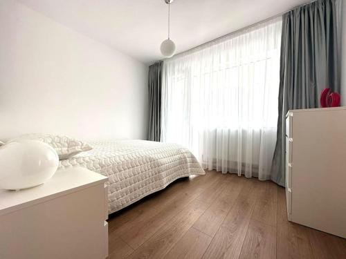 a white bedroom with a bed and a large window at Carolina Residence in Alba Iulia