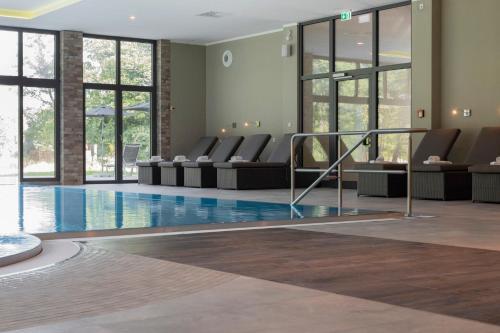 a hotel lobby with a pool with chairs and windows at Landhotel Burg im Spreewald - Resort & Spa in Burg