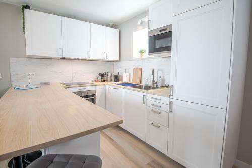 a kitchen with white cabinets and a wooden counter top at Le cosy pad in Amboise
