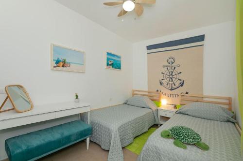 1 dormitorio con 2 camas, mesa y ventilador en Lovely Spacious Apartment in San Isidro Tenerife, en San Isidro