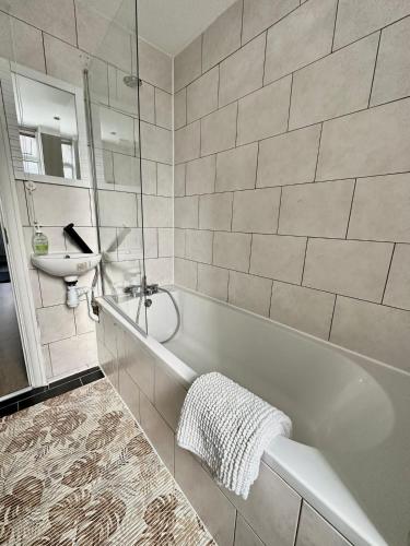 La salle de bains est pourvue d'une baignoire blanche et d'un lavabo. dans l'établissement westcliff on sea, à Southend-on-Sea