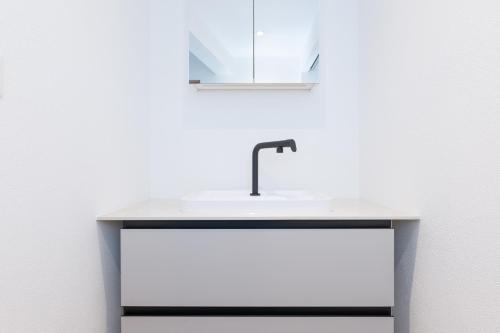 een witte wastafel met een spiegel erop bij 2,5 Zimmer Ferienwohnung mit Küche/Bad in Triesen
