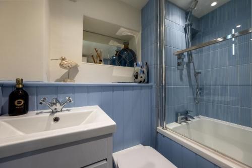 a bathroom with a sink and a toilet and a tub at Bracken Cottage in Brancaster