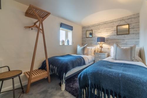 a bedroom with two beds and a table and a chair at Bracken Cottage in Brancaster