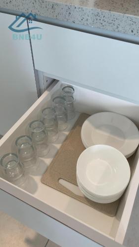 a row of glass bowls and plates in a drawer at Urban Suites Georgetown by BNB4U in Jelutong
