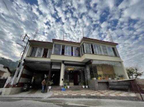 a man standing in front of a house at Hotel Nature’s View Loharkar in Dharmsala