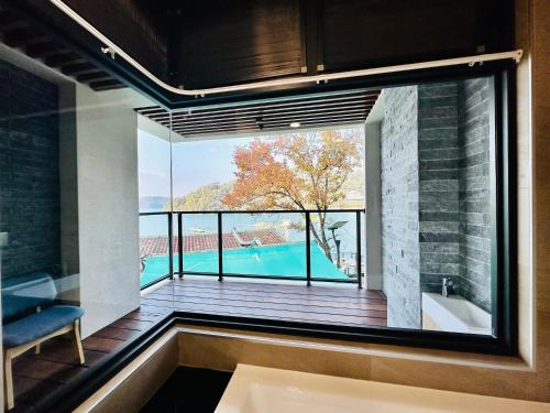 un bagno con una grande finestra che si affaccia su una piscina di 水秀一方Sun Moon Lakeside Boutique Hotel a Yuchi