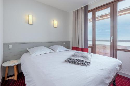Schlafzimmer mit einem weißen Bett und einem großen Fenster in der Unterkunft Résidence Pierre & Vacances Antarès in Avoriaz