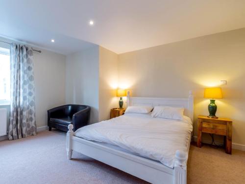 a bedroom with a white bed and a black chair at 4 Bed in Langtoft 81235 in Weaverthorpe