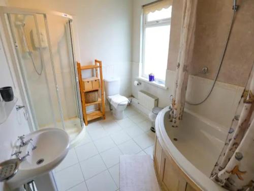 a bathroom with a tub and a sink and a shower at Pass the Keys Spacious and Comfortable 3 Bed Home in Birkenhead in Birkenhead