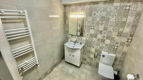 uma casa de banho com um WC, um lavatório e um espelho. em Aqua Apartament Mamaia em Mamaia