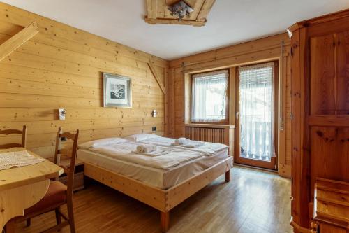 1 dormitorio con 1 cama y pared de madera en Nord Hotel, en Cortina dʼAmpezzo