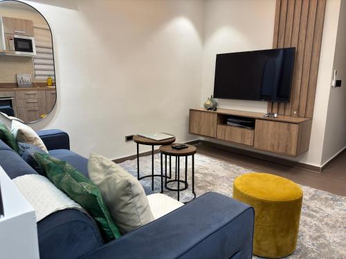 sala de estar con sofá azul y TV de pantalla plana en Studio Apartment en Accra