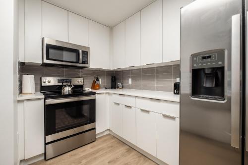 uma cozinha com armários brancos e um frigorífico de aço inoxidável em CityScape Flat- 3BR Luxury APT in Uptown em Charlotte