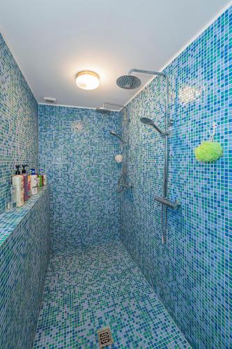 a bathroom with blue tiled walls and a shower at Spacious Studio apartment by Polo apartments in Kaunas