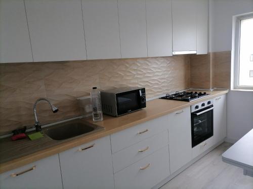 a kitchen with white cabinets and a sink and a microwave at Luxury 4-rooms, 2-bathrooms, Obor area in Bucharest