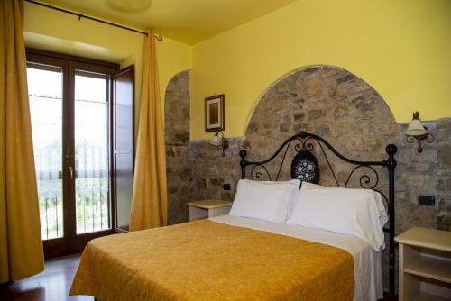 1 dormitorio con cama y pared de piedra en La Foresteria di San Leo en Trivigno