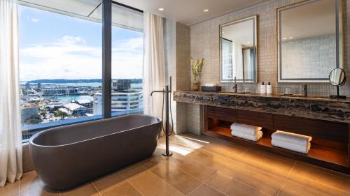 InterContinental Auckland, an IHG Hotel في أوكلاند: حمام مع حوض استحمام و نافذة كبيرة