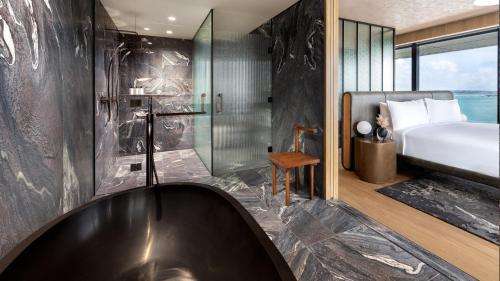 InterContinental Auckland, an IHG Hotel في أوكلاند: حمام مع حوض استحمام وسرير ودش