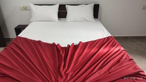 a bed with a red blanket on top of it at Laxsume Guest House Nilaveli in Nilaveli