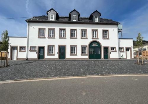 a large white building with green doors on a street at Feriendomizil im Saarschleifenland in Mettlach