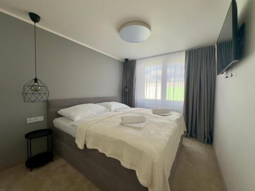 a bedroom with a bed with white sheets and a window at Apartmán Olívia in Šamorín