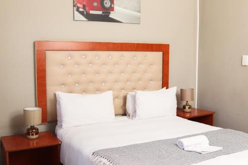 a bedroom with a large bed with white sheets and two lamps at Mohlaletse Guest House in Ga-Matsi