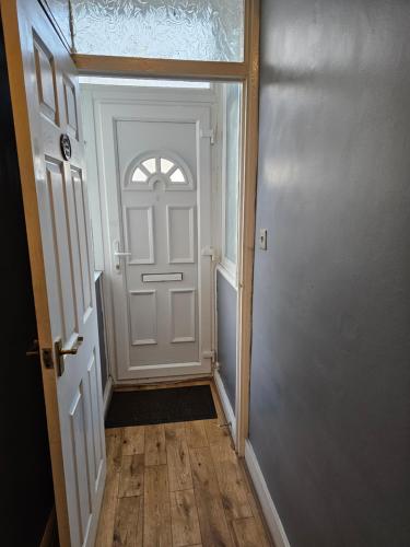a hallway with a white door and a wooden floor at Umbrella Properties London Excel in London