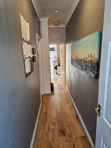 a hallway with a wooden floor and a painting on the wall at Umbrella Properties London Excel in London
